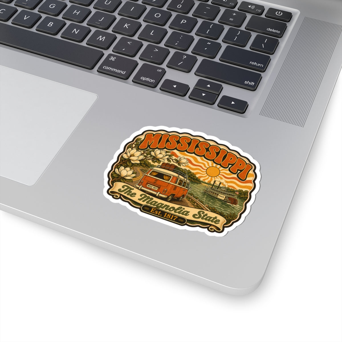 Mississippi retro state sticker on a laptop trackpad, featuring orange van and riverboat art