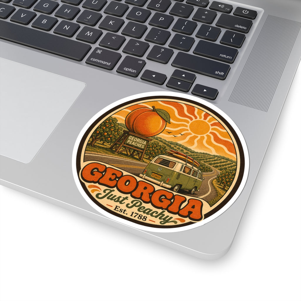 Round vinyl sticker on laptop lid close-up, showing Georgia Just Peachy and green van art
