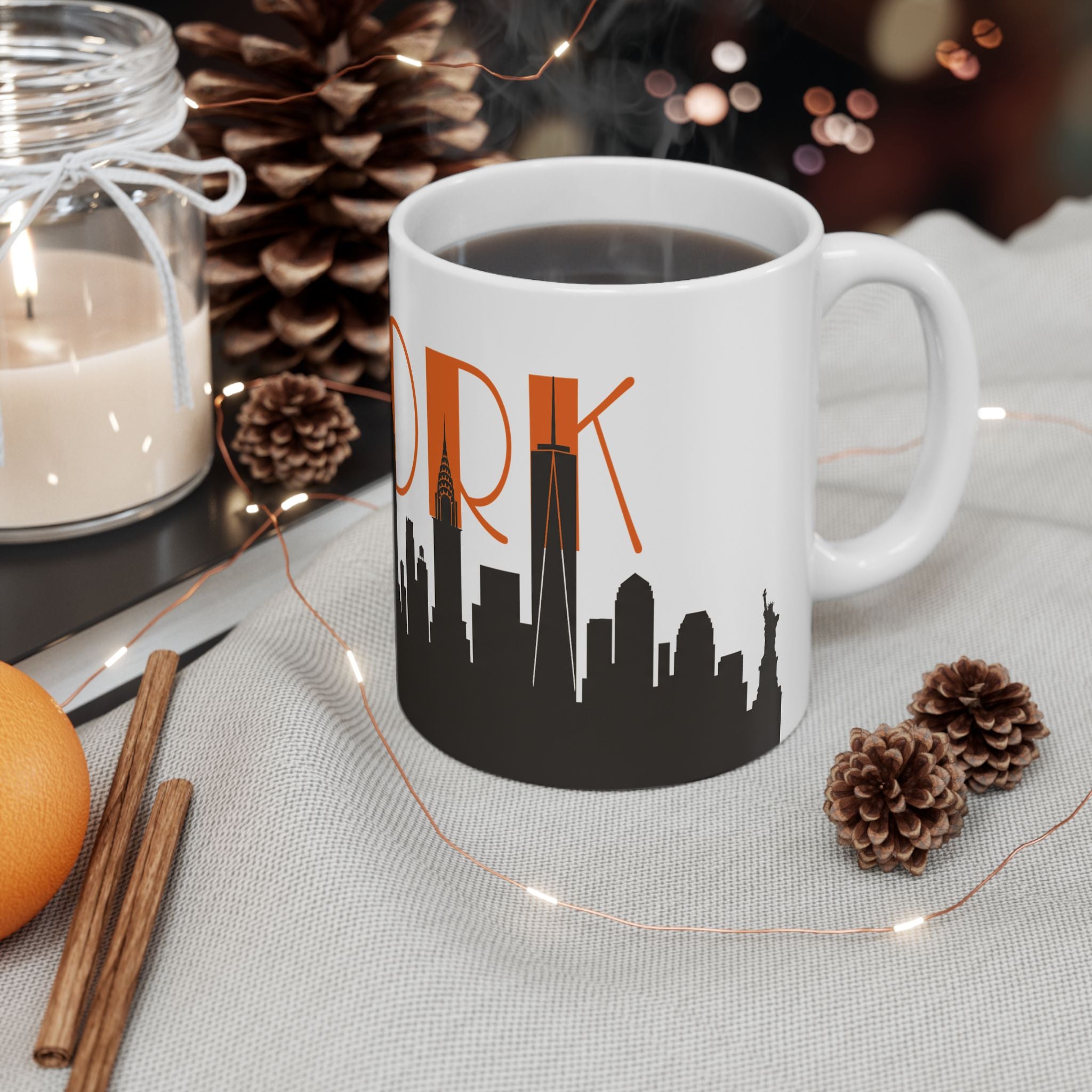 White ceramic coffee mug with orange “ORK” text and black skyline on table