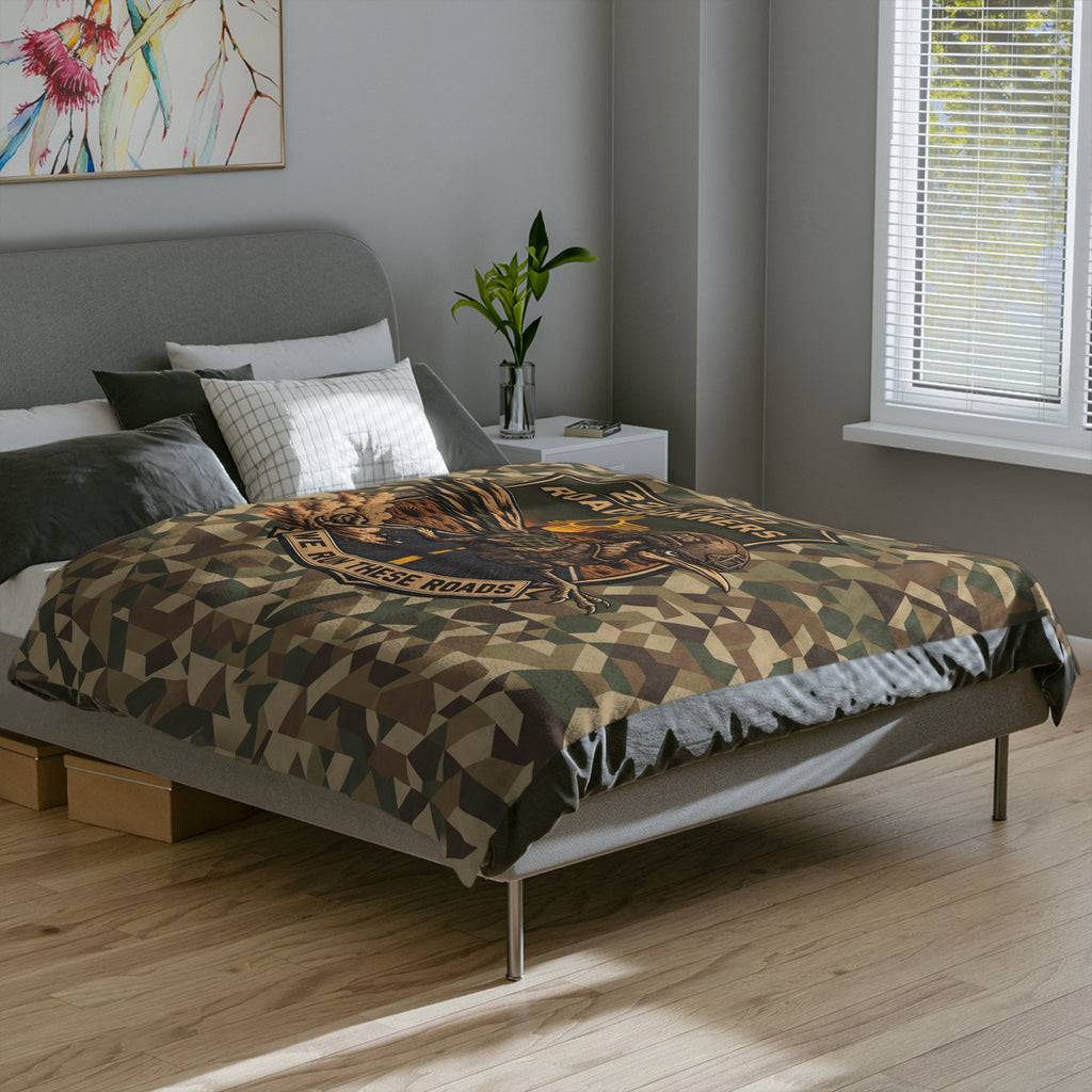 Camo microfiber blanket with central embroidered runner graphic and geometric pattern on bed