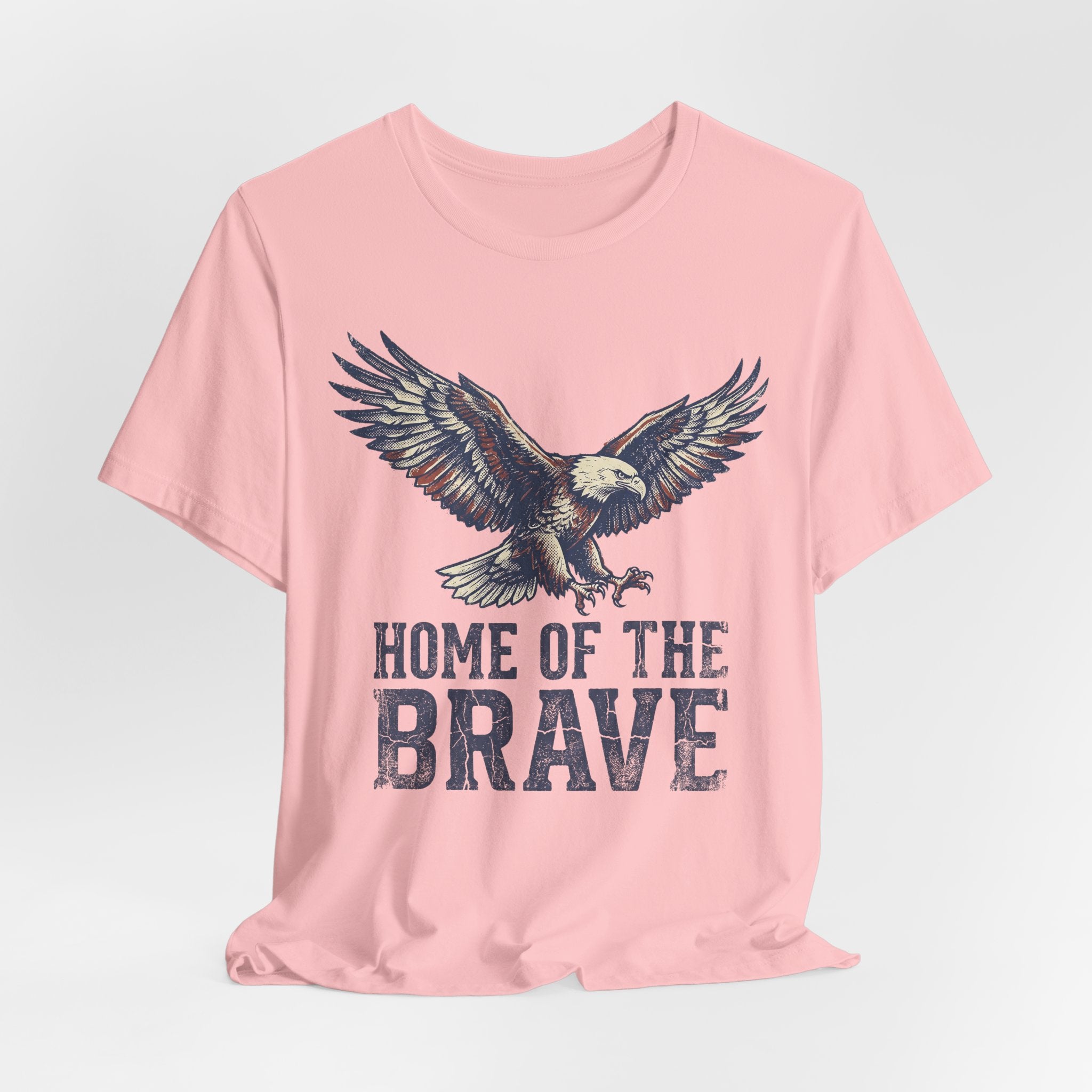 Soft pink crew-neck T-shirt with eagle and 'HOME OF THE BRAVE' text.