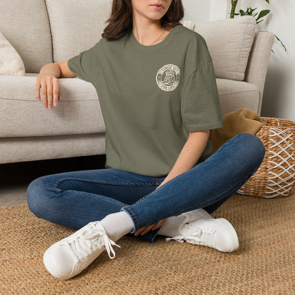 Olive green T-shirt with veteran seal logo on left chest, worn with jeans and white sneakers.