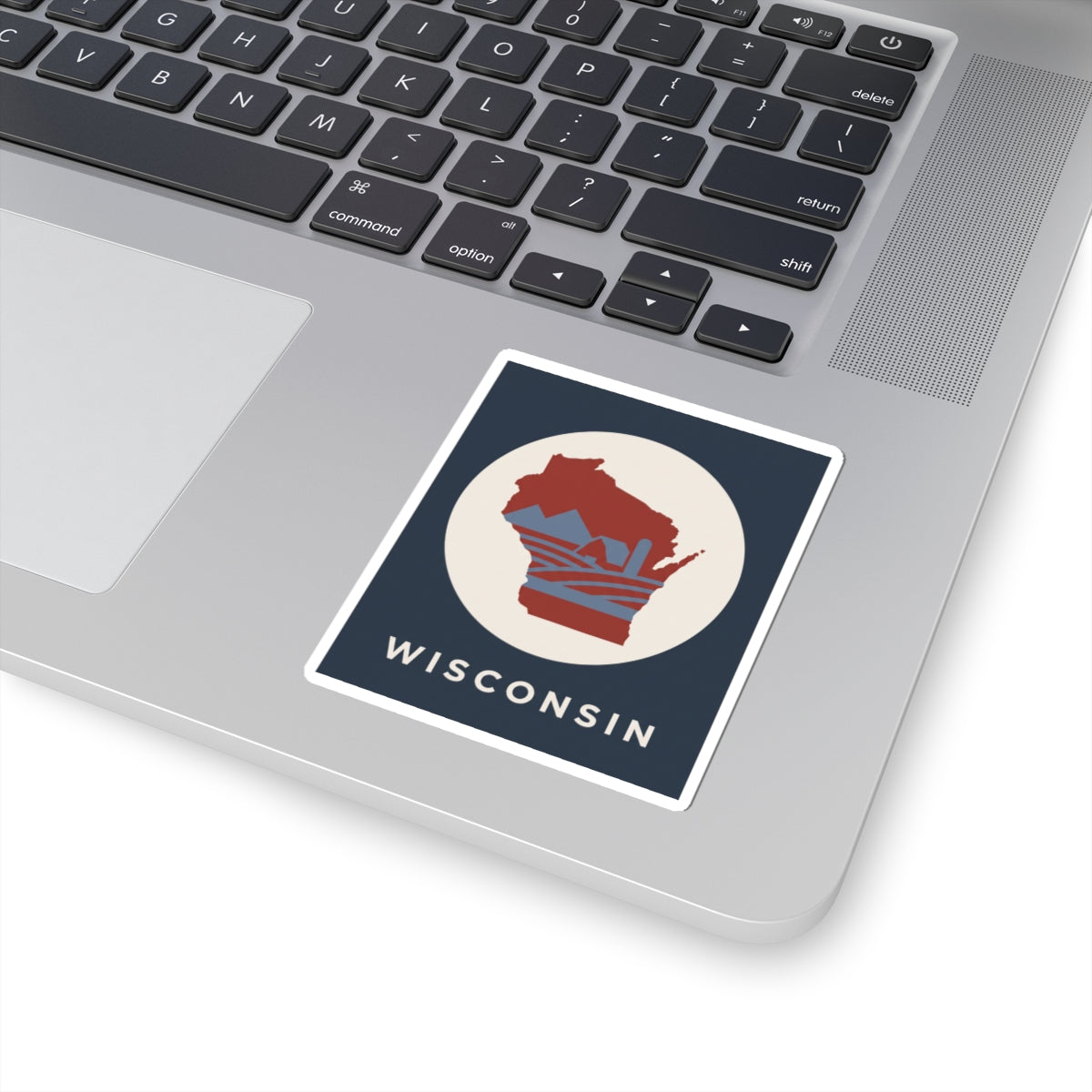 Wisconsin badge sticker on laptop: red Wisconsin map in cream circle with WISCONSIN text