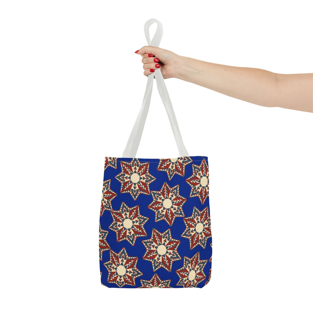 Blue starburst floral tote bag with white handles held up by one hand