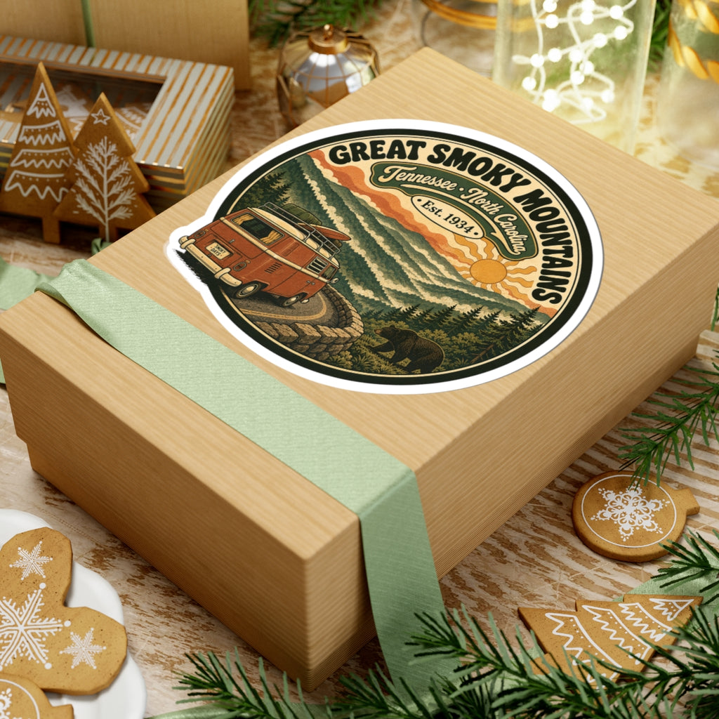 Round sticker on a gift: vintage camper van on mountain road with layered hills and trees