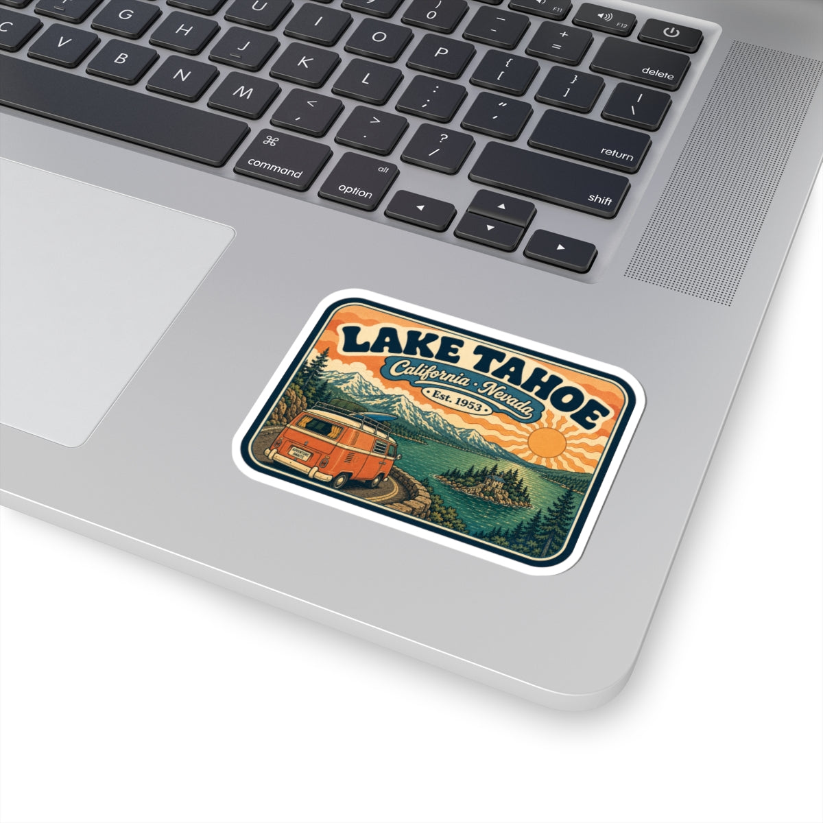 Kiss-cut Lake Tahoe sticker on a laptop keyboard, vintage camper van and mountain lake graphic.