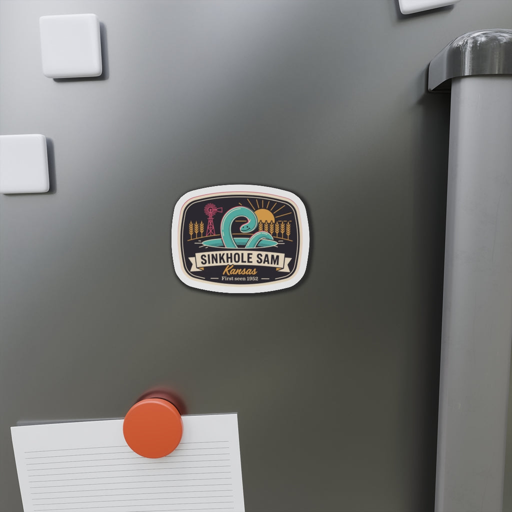 Die-cut sticker-style magnet on refrigerator door, small oval Kansas scenic graphic