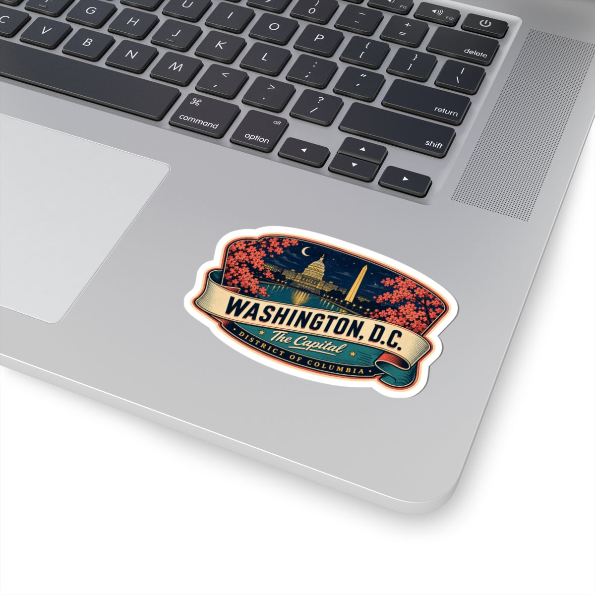 Luggage tag sticker on a laptop showing Washington D.C. landmarks, pink blossoms, and The Capitol