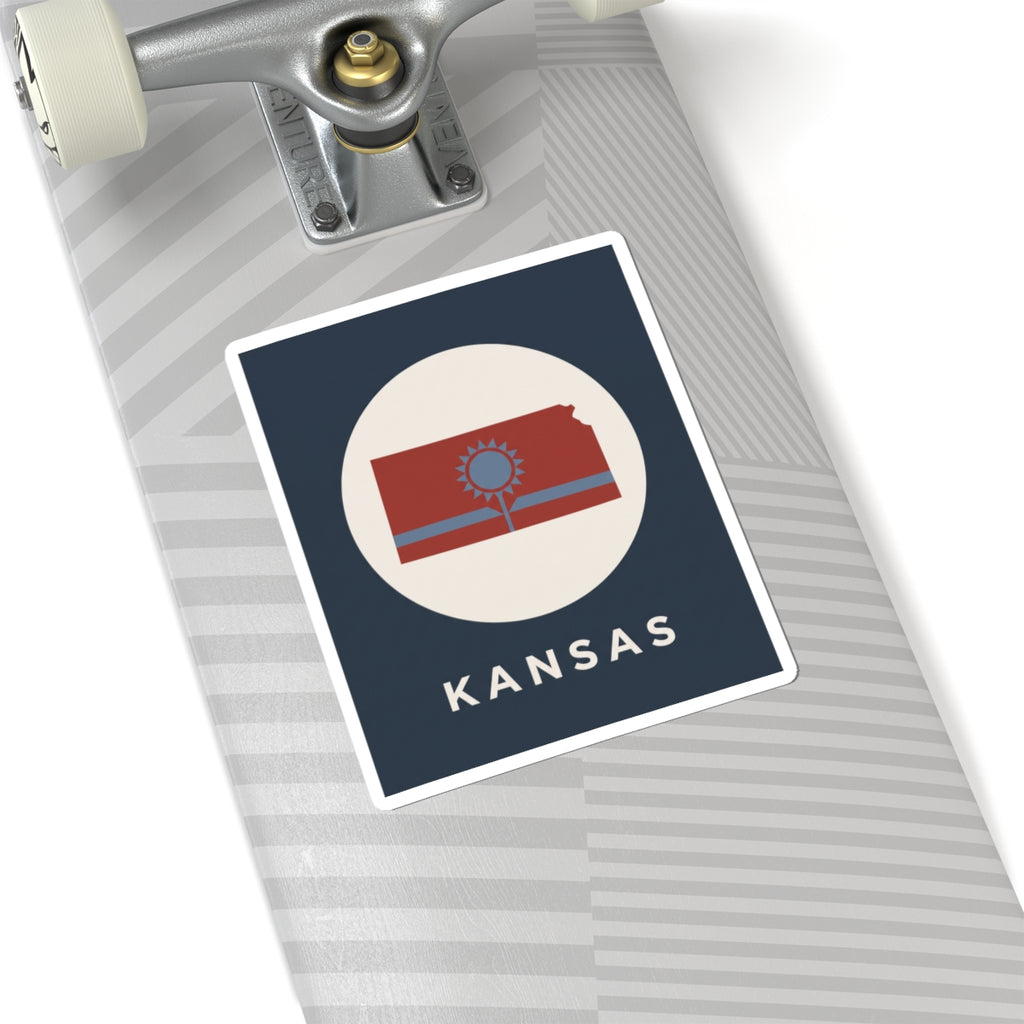 Kansas sunflower state sticker on light stripes, blue background, “KANSAS” text and emblem