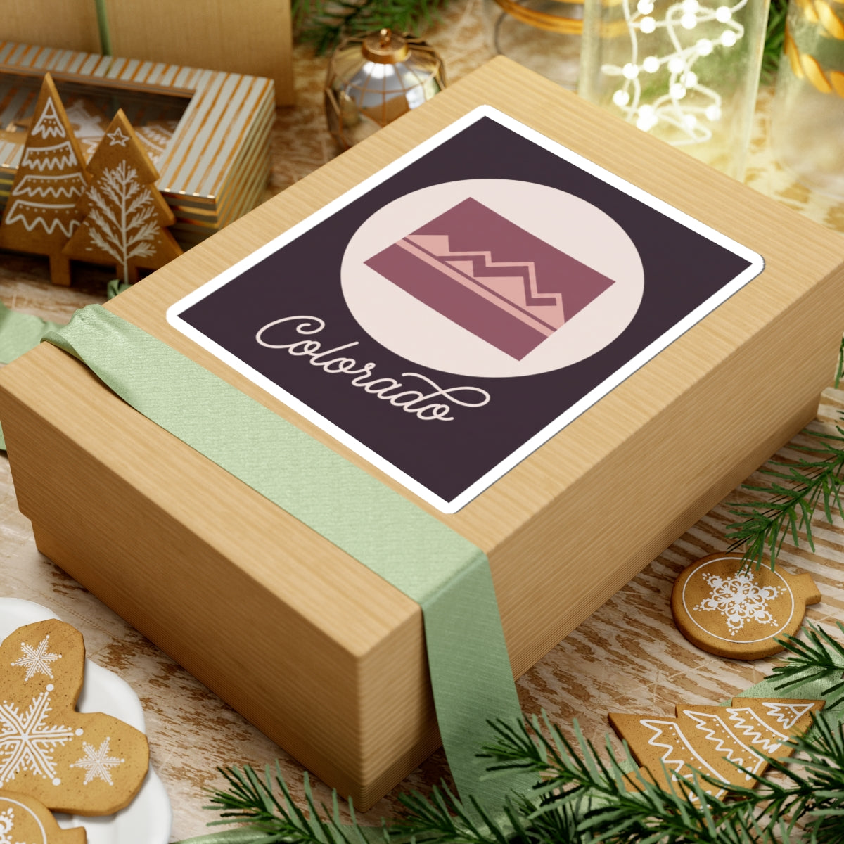 Colorado sticker on a wrapped gift: dark purple square with mauve landscape and “Colorado”