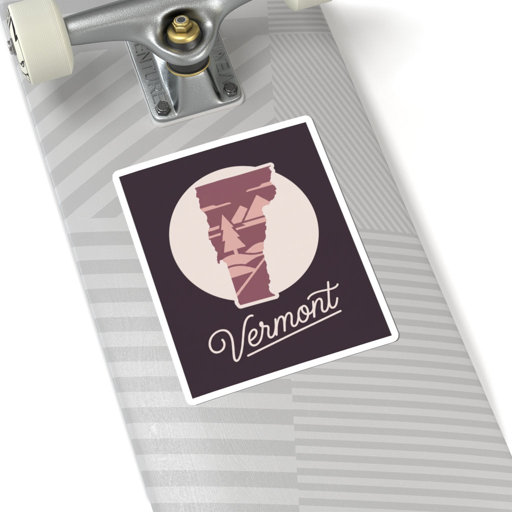 Vermont state silhouette sticker with maroon pine artwork and cursive 'Vermont' on light surface