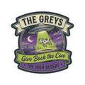 Sticker badge shows green cow under UFO at night, text 'THE GREYS' and 'THE HIGH DESERT'.