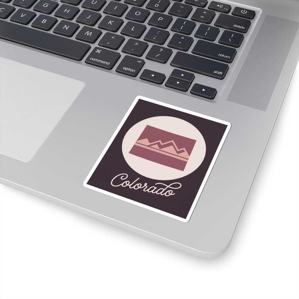 Colorado vinyl decal on a laptop: dark square with mauve landscape and “Colorado” script