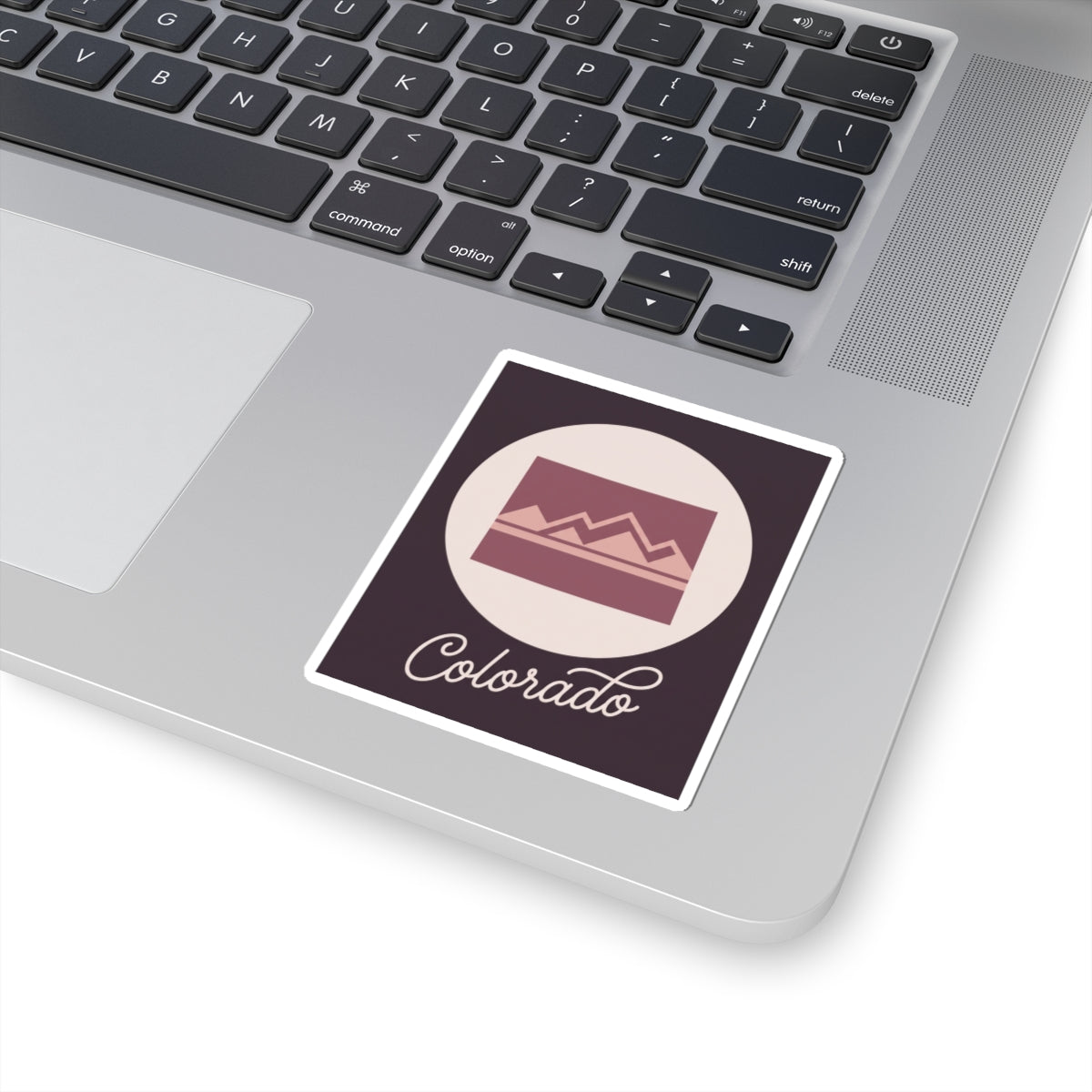Colorado vinyl decal on a laptop: dark square with mauve landscape and “Colorado” script