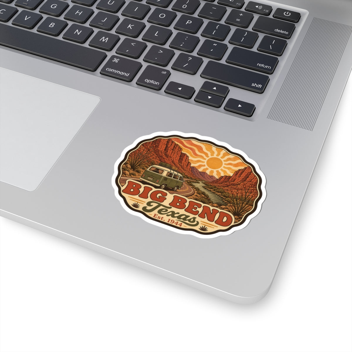 Die-cut road trip sticker on a laptop showing Big Bend Texas desert and vintage camper
