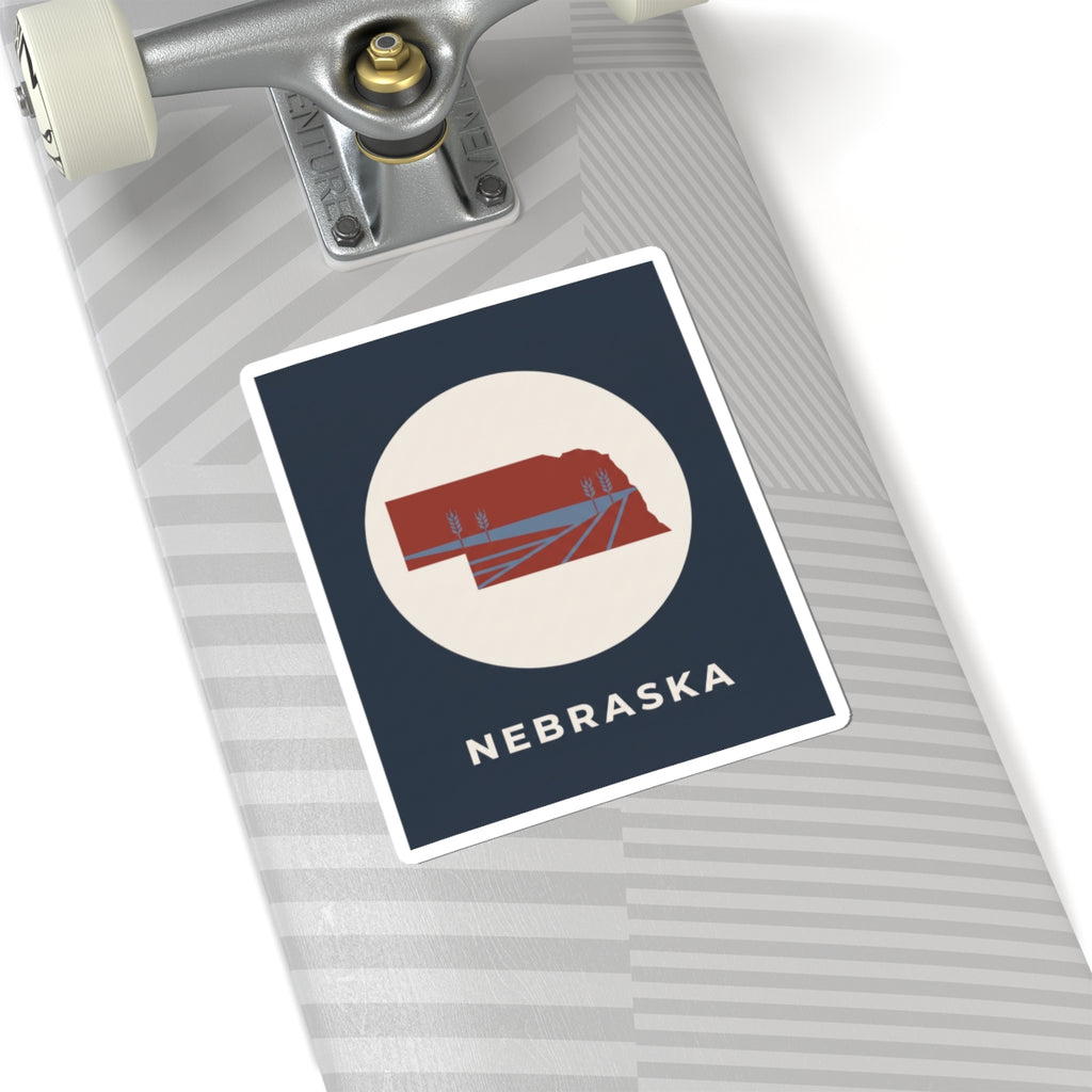 Nebraska sticker with red Nebraska farmland map inside white circle on navy square