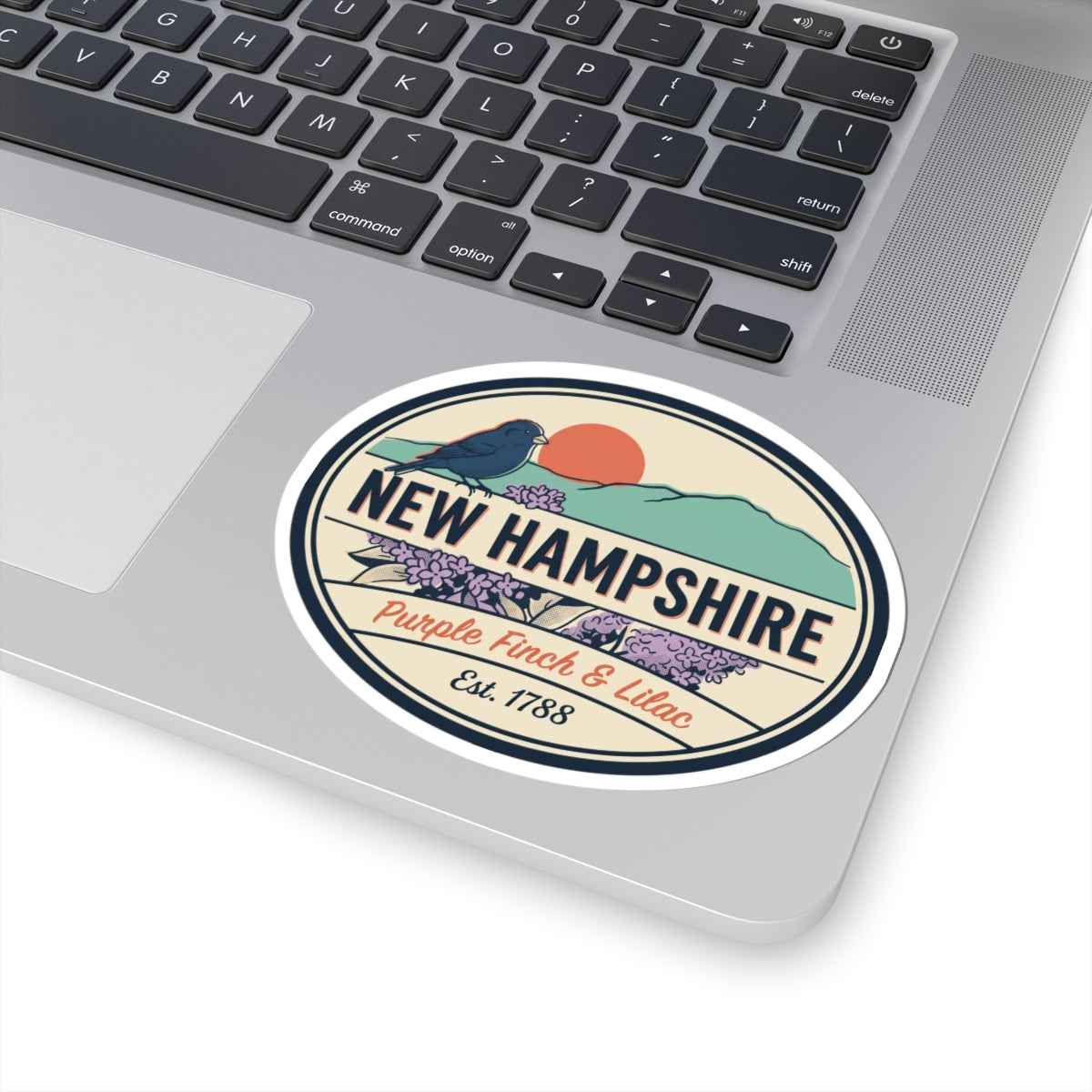 Round New Hampshire sticker on laptop lid showing purple finch & lilac, Est. 1788
