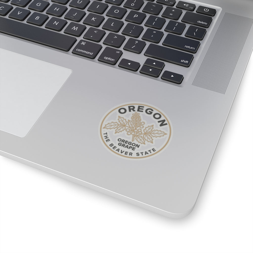 Transparent Oregon grape sticker on a laptop lid, circular 'OREGON' and 'OREGON GRAPE' text