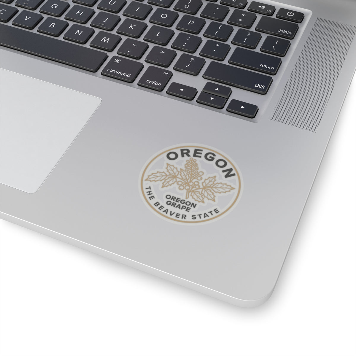 Transparent Oregon grape sticker on a laptop lid, circular 'OREGON' and 'OREGON GRAPE' text