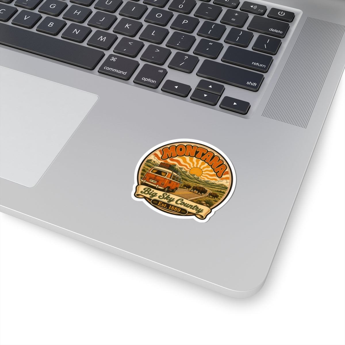 Round vintage-style Montana sticker with camper and retro sunset design on laptop
