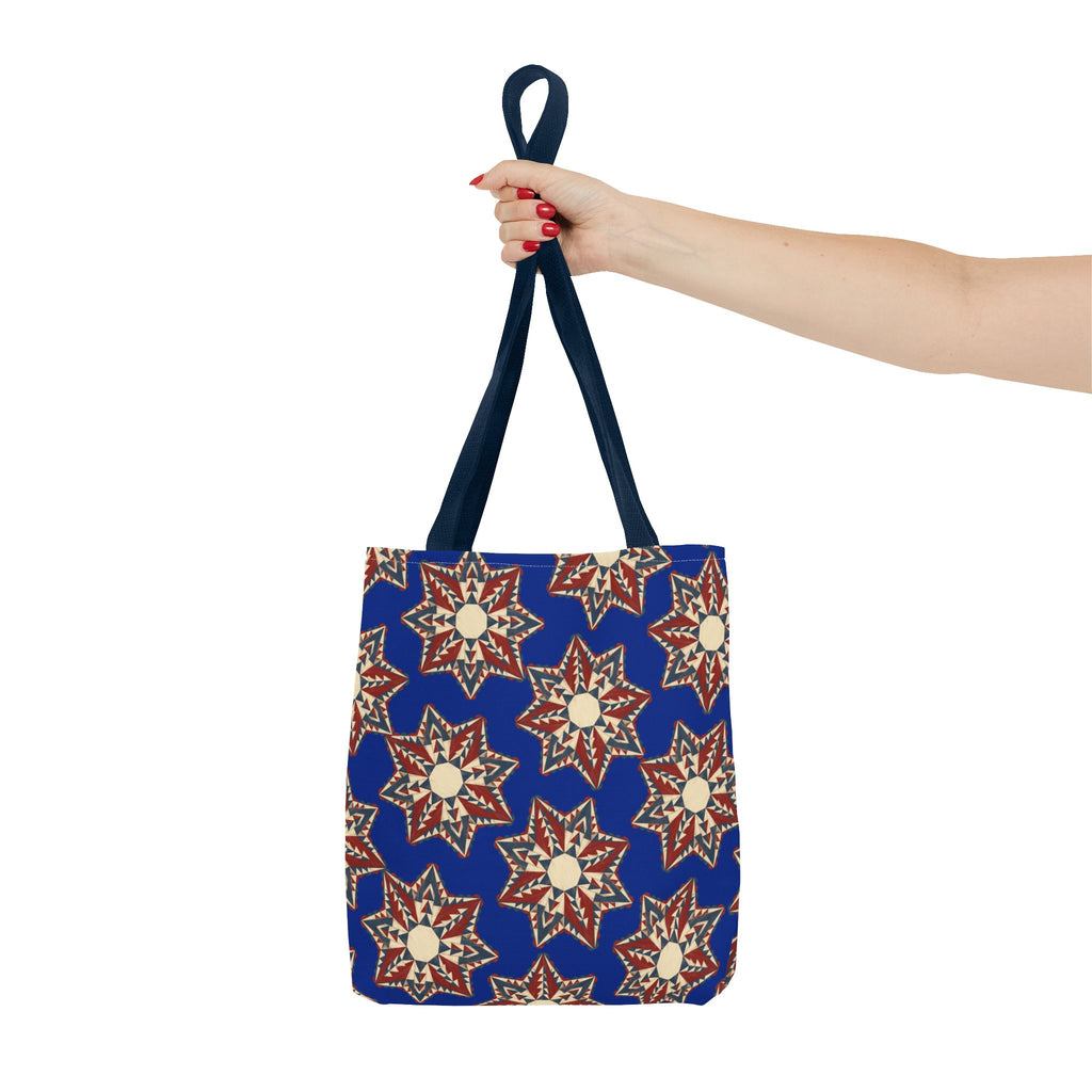 Blue tote bag with red and cream starburst floral print, held by navy top handle.
