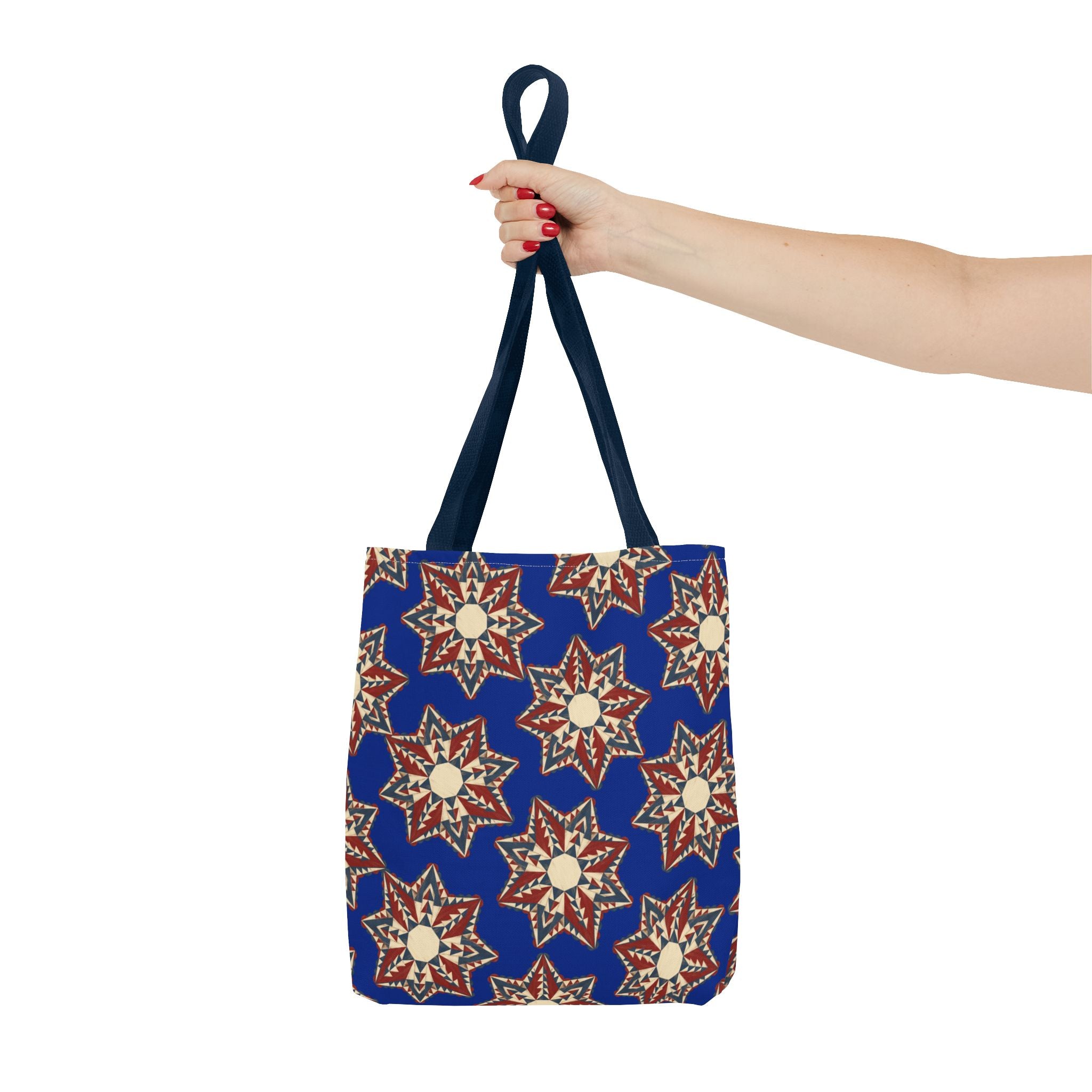 Blue tote bag with red and cream starburst floral print, held by navy top handle.