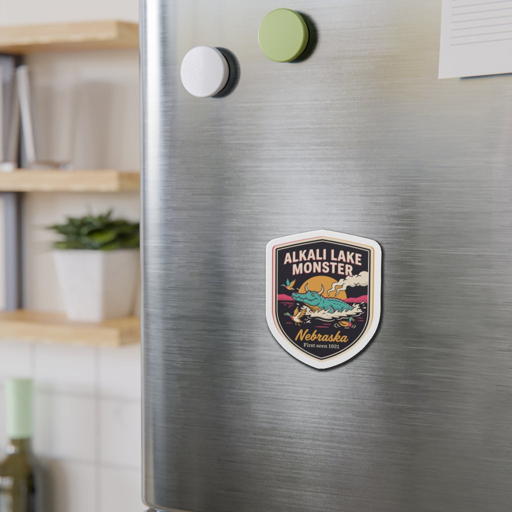 Shield-shaped die-cut magnet on a stainless refrigerator, featuring Nebraska badge artwork
