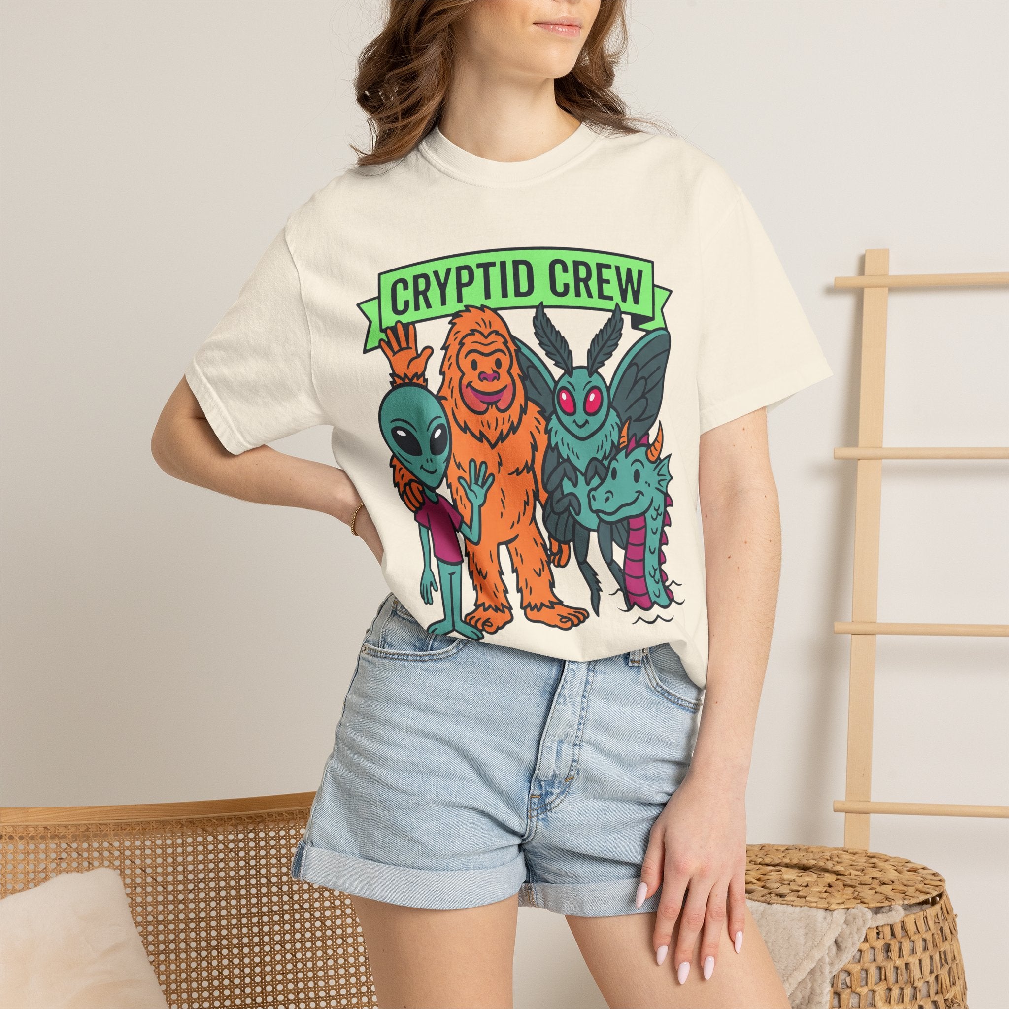 Ivory crew-neck T-shirt with colorful “Cryptid Crew” graphic of four alien cryptids