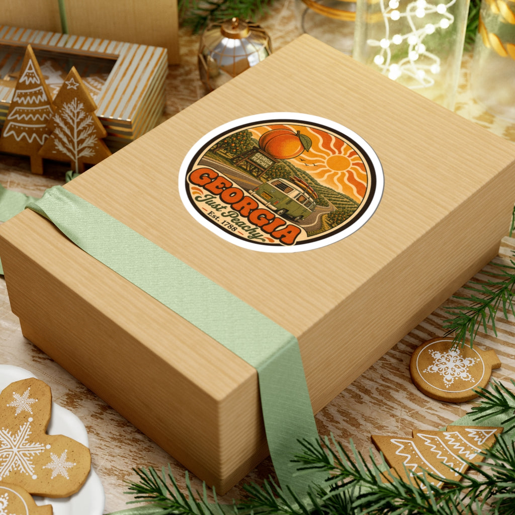 Round vinyl sticker on tan gift box lid, with Georgia Just Peachy orange fruit and green van