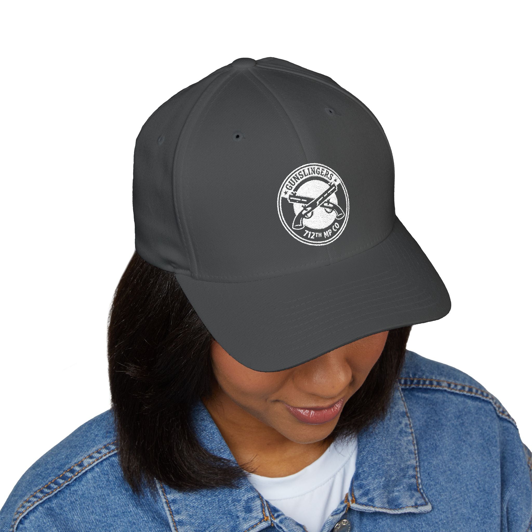 Embroidered baseball cap in dark grey with white circular emblem on front panel.