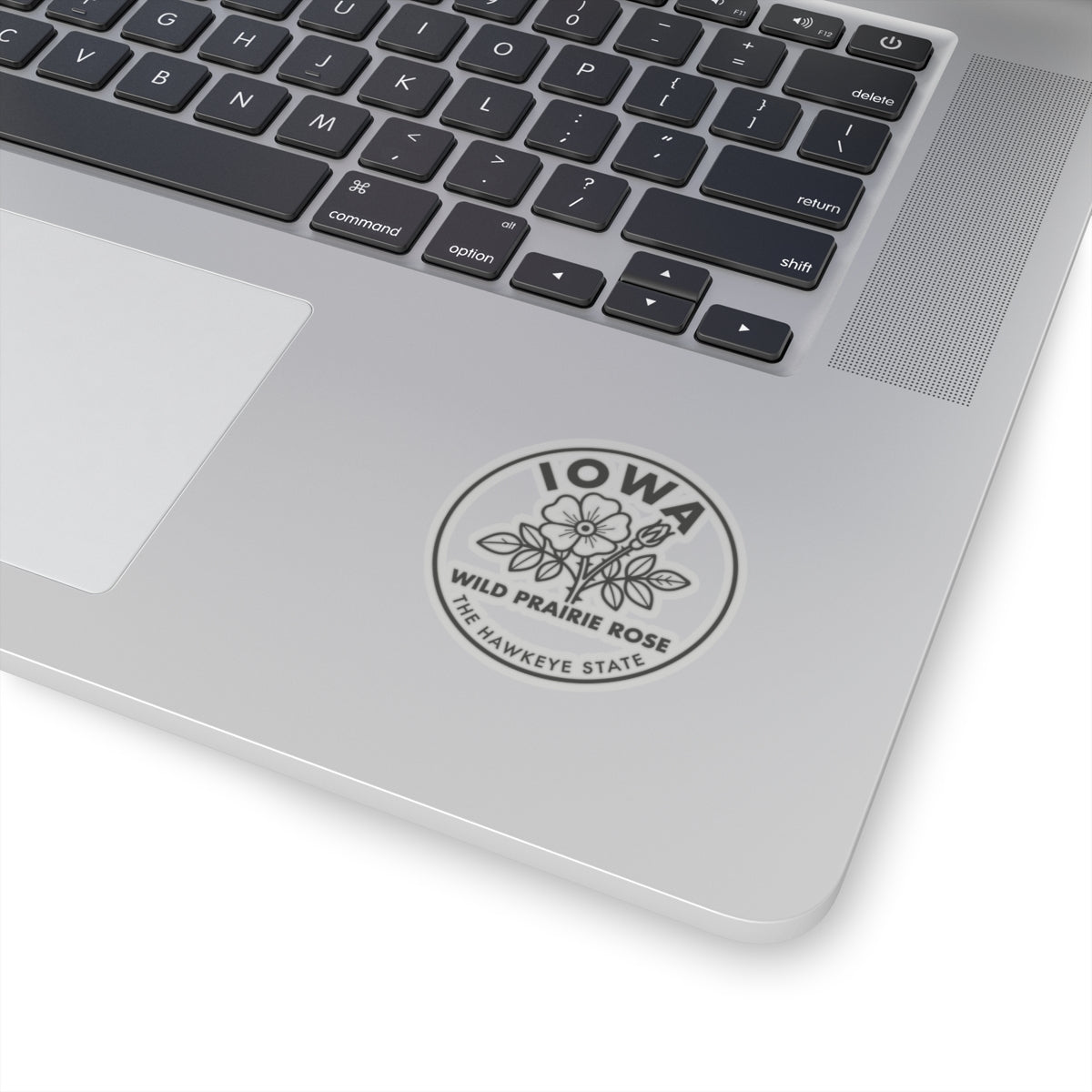 Circular vinyl sticker on laptop lid showing Iowa wild prairie rose and hawkeye state