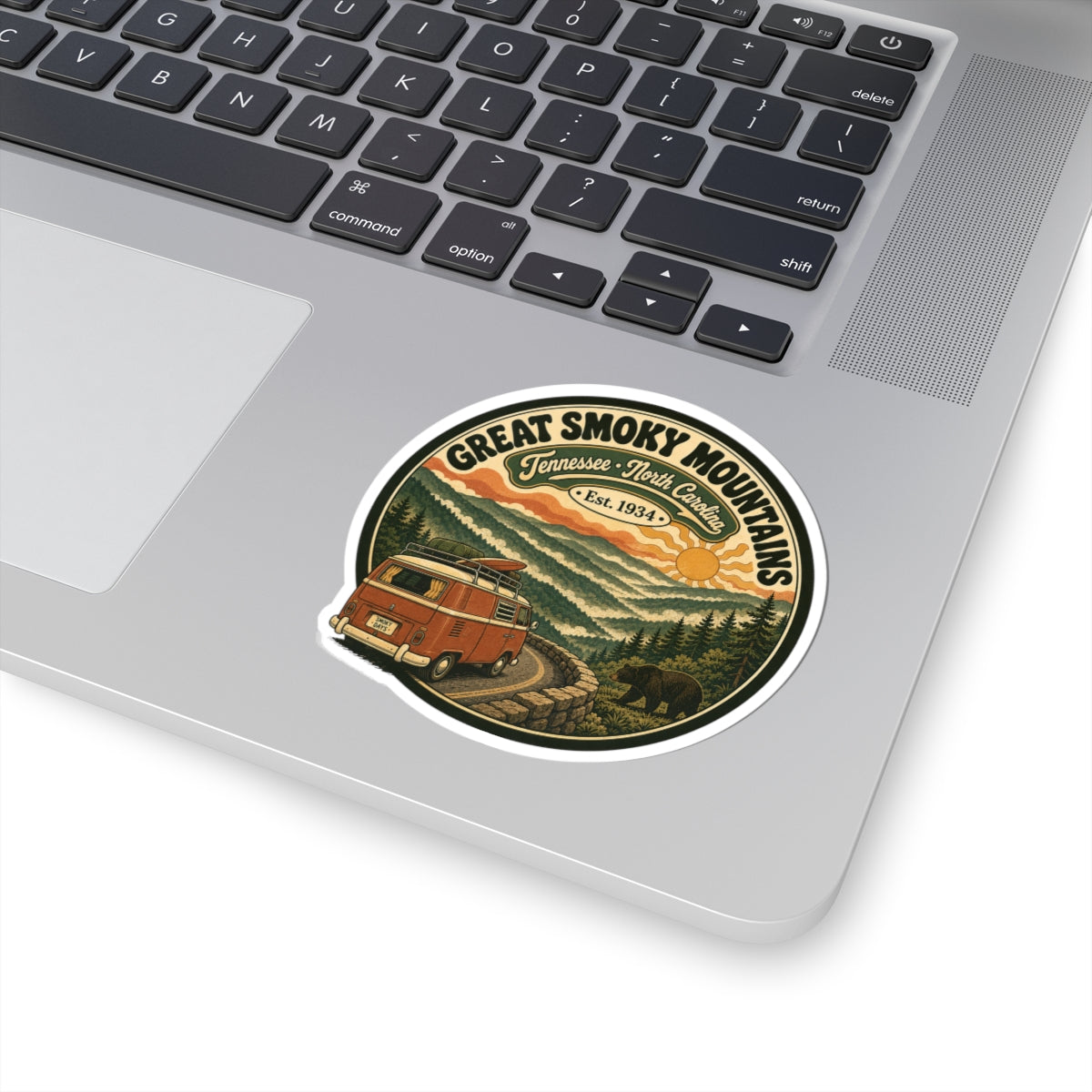 Round die-cut sticker with vintage camper van on winding road in forest mountains