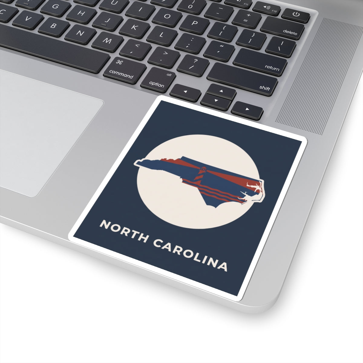 North Carolina state kiss-cut sticker on laptop, navy square with red-and-blue map