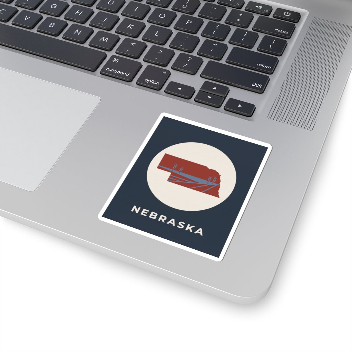 Nebraska sticker with red map and farmland lines on a navy square, white border