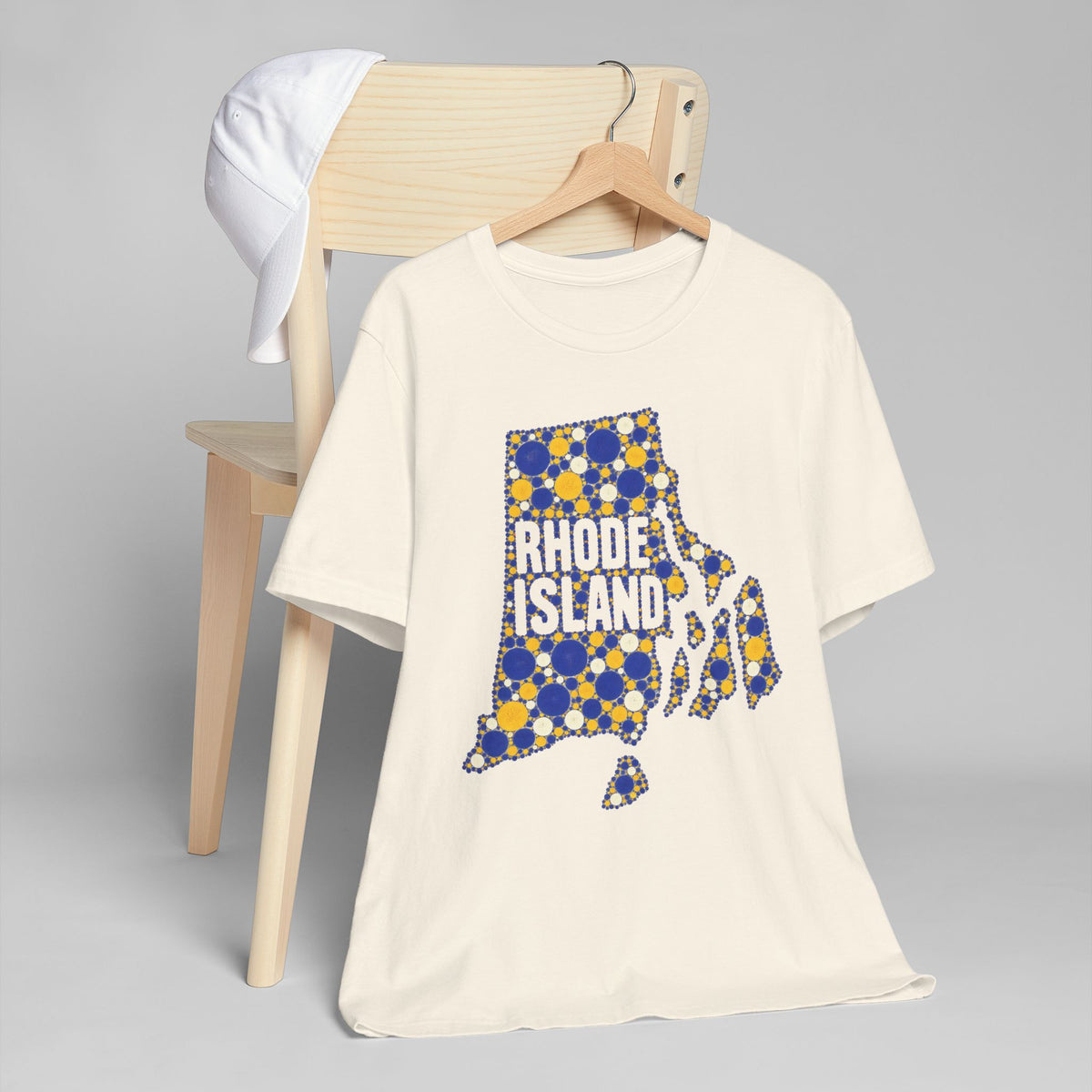 Cream crew-neck T-shirt with blue and yellow dotted Rhode Island state outline graphic.