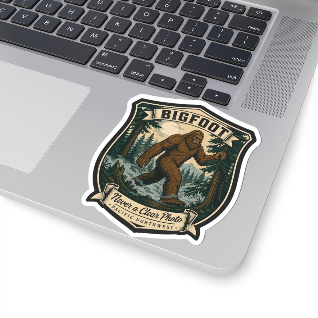 Bigfoot hiking badge sticker on laptop, shield design with “Never a Clear Photo” text