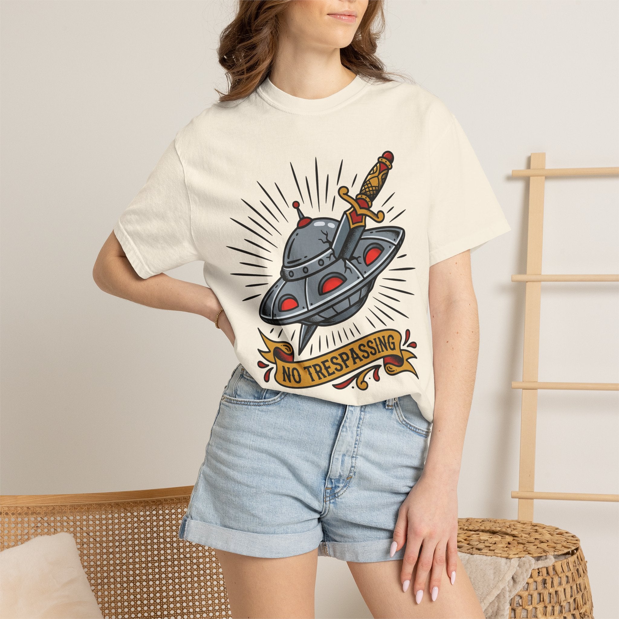 Ivory T-shirt with cartoon UFO and dagger graphic and “No Trespassing” badge
