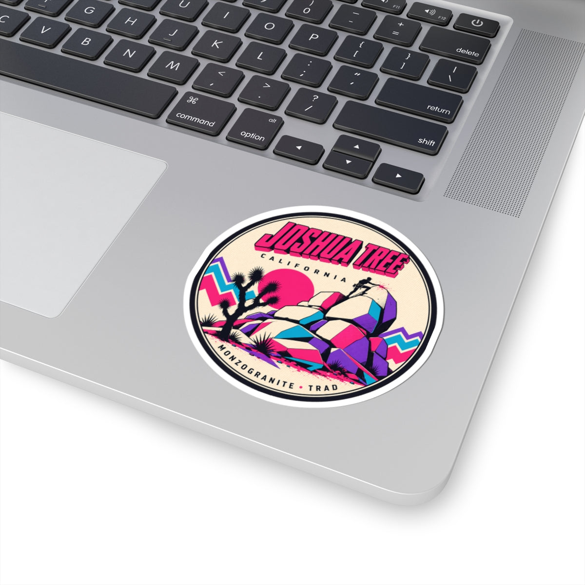 Round vinyl sticker on laptop surface, colorful desert rock formation with Joshua tree art.