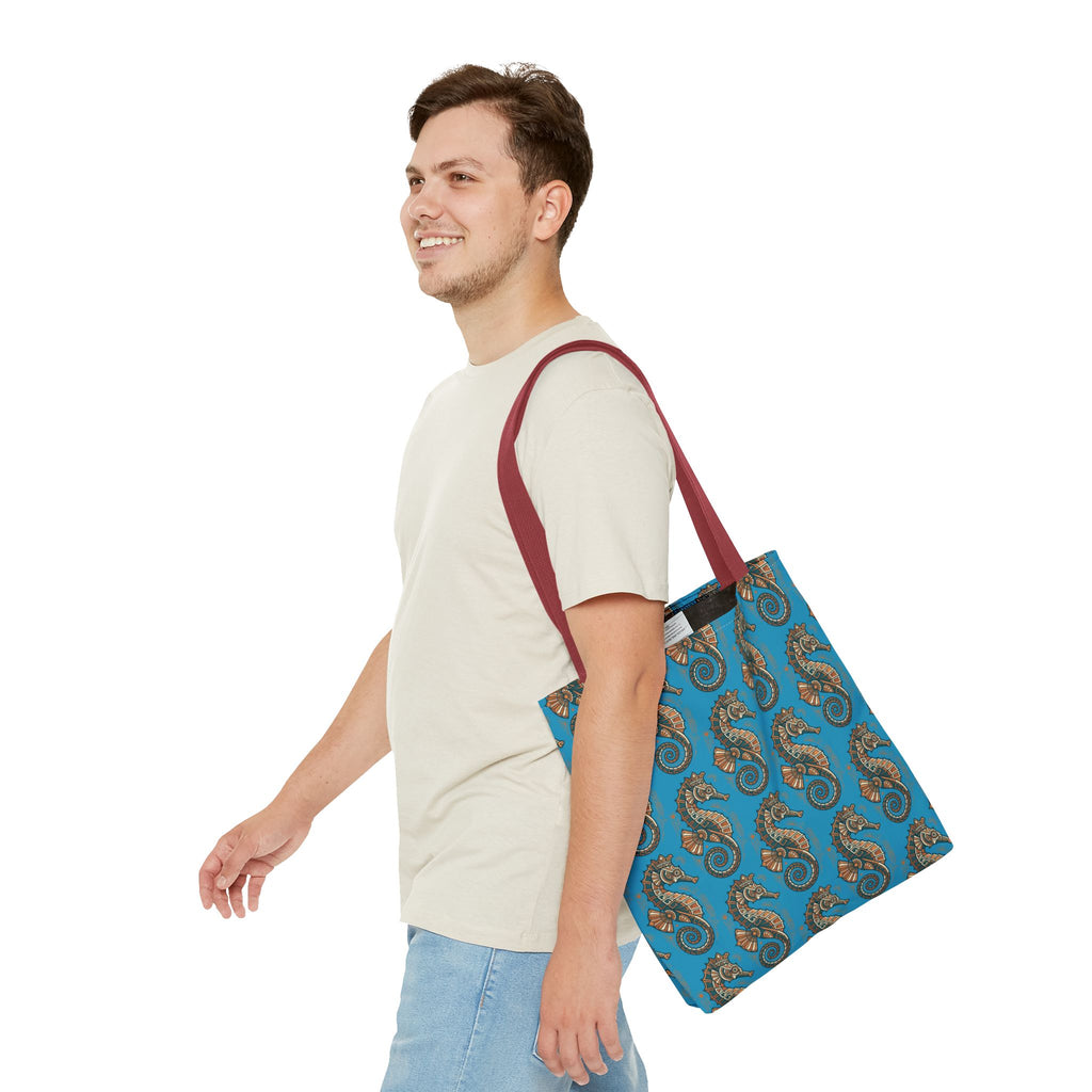 Tote bag worn on shoulder in blue with seahorse pattern and red straps