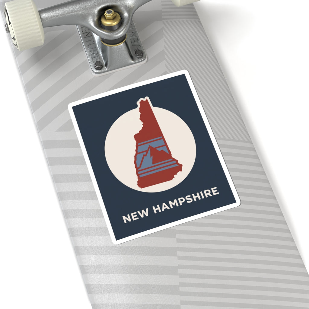 New Hampshire state silhouette sticker on a roller case: navy label with red map in white circle