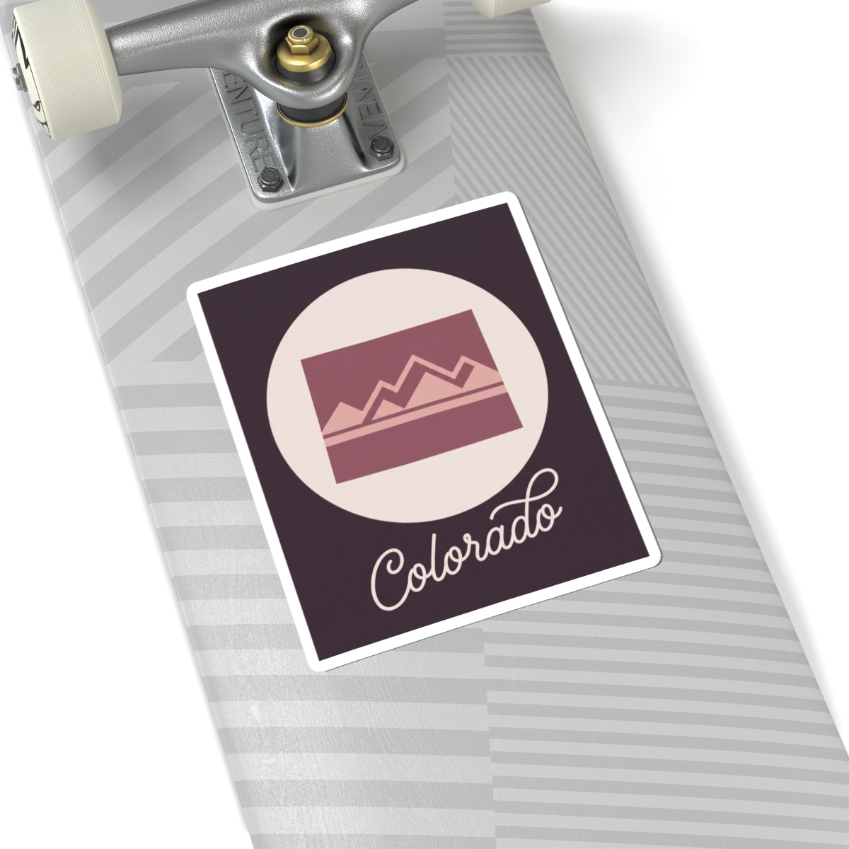Colorado sticker on a roller suitcase, dark square with mauve landscape icon and “Colorado”