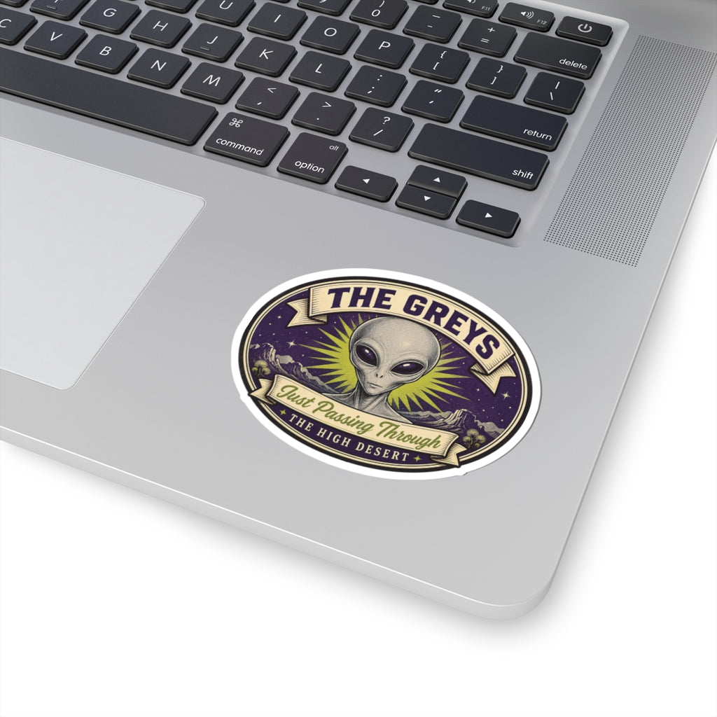 Alien head circular sticker on a laptop surface, purple starry design with “THE GREYS” banner