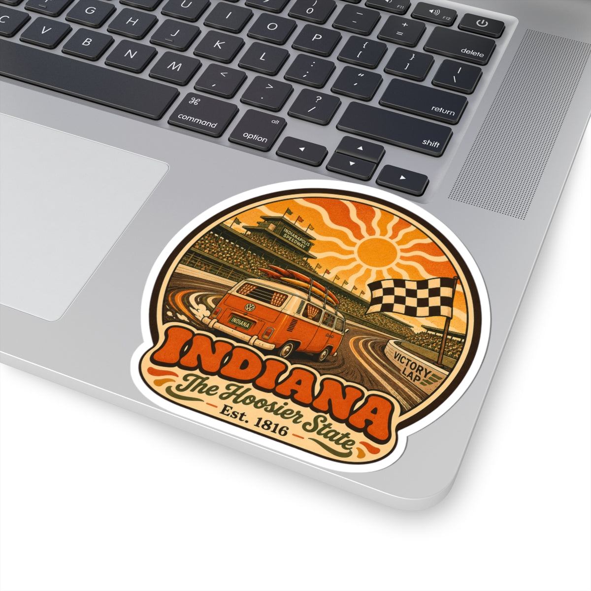 Circular decal on laptop keyboard showing orange VW van, Victory Lap sign, and Indiana text