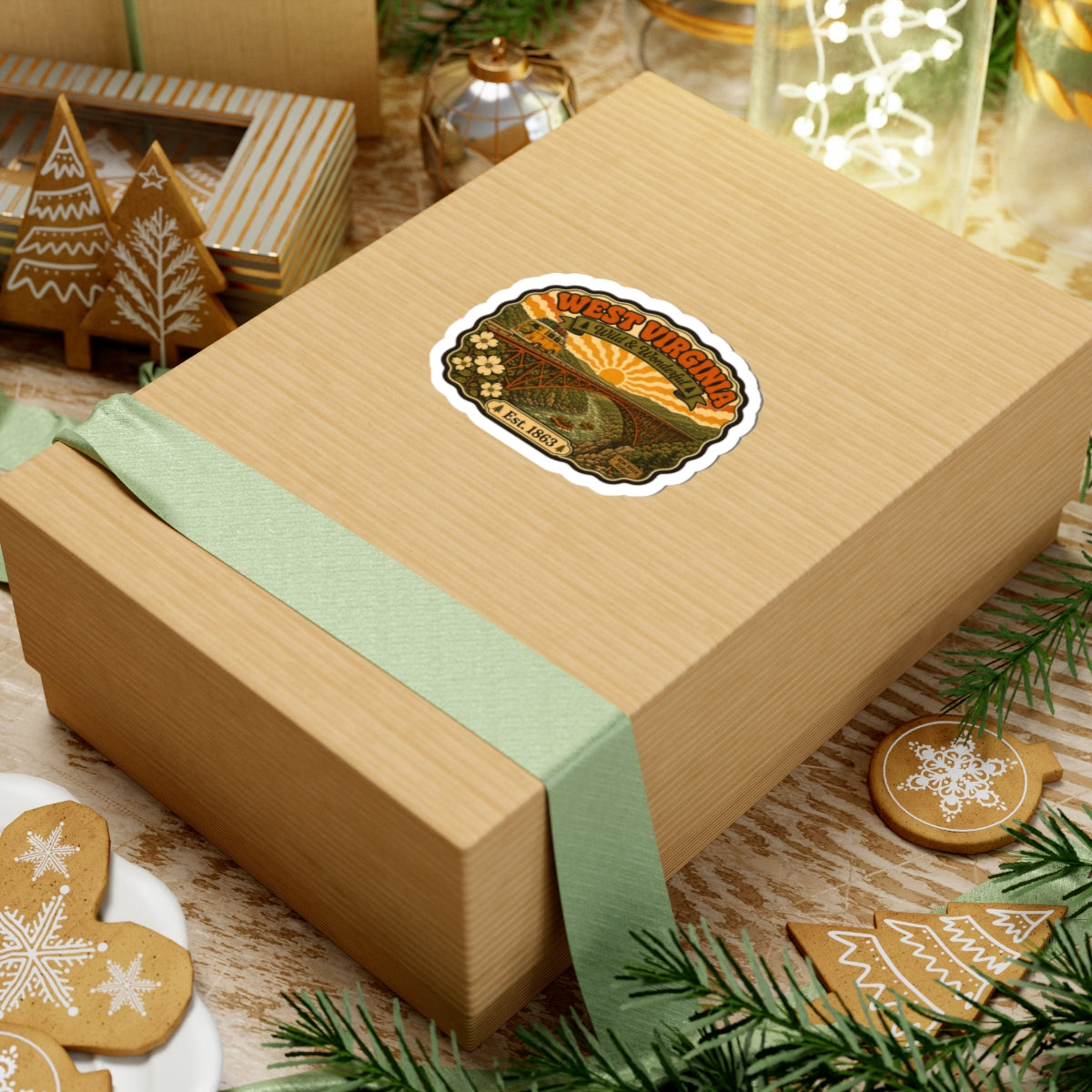 West Virginia kiss-cut sticker on a gift box, with bridge scene, sun, wildflowers, Est. 1863.
