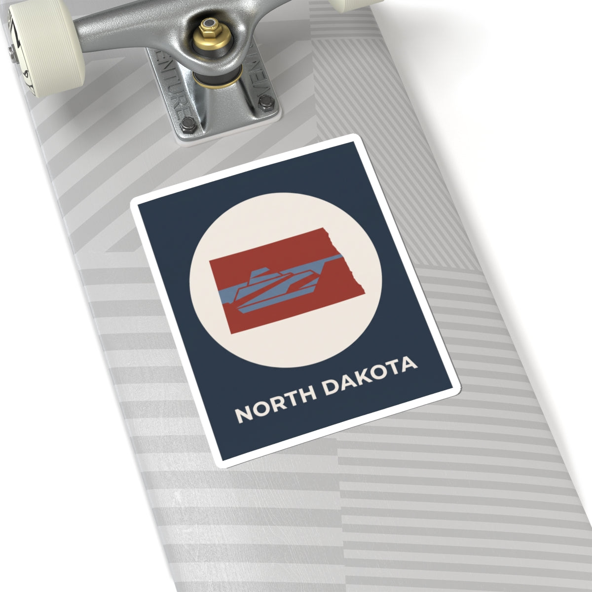 North Dakota map sticker on a notebook, navy square with cream circle and red state graphic
