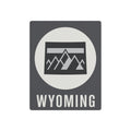 Wyoming metal wall sign with dark gray background, white circle, mountain graphic, and WYOMING text