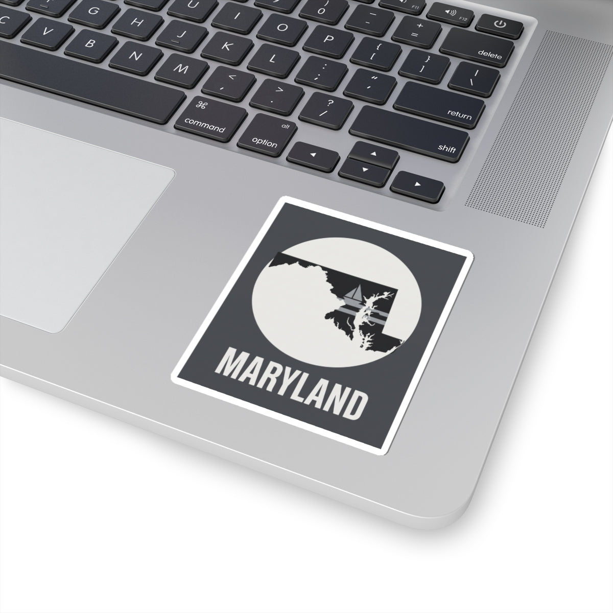 Maryland kiss-cut sticker on a laptop, showing circular state silhouette and “MARYLAND”
