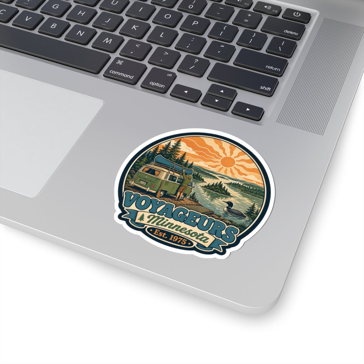 Round die-cut sticker with green camper van landscape, pine trees, lake, orange sun; Est. 1975