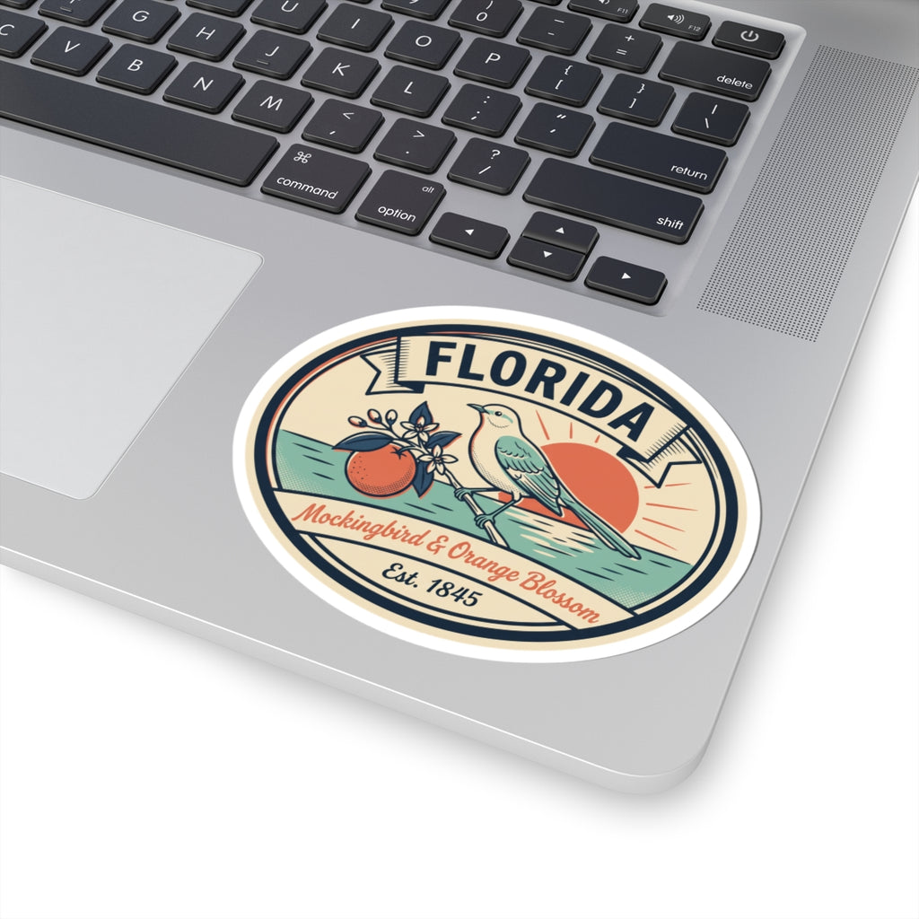 Circular Florida badge sticker on a laptop, featuring mockingbird and orange blossom