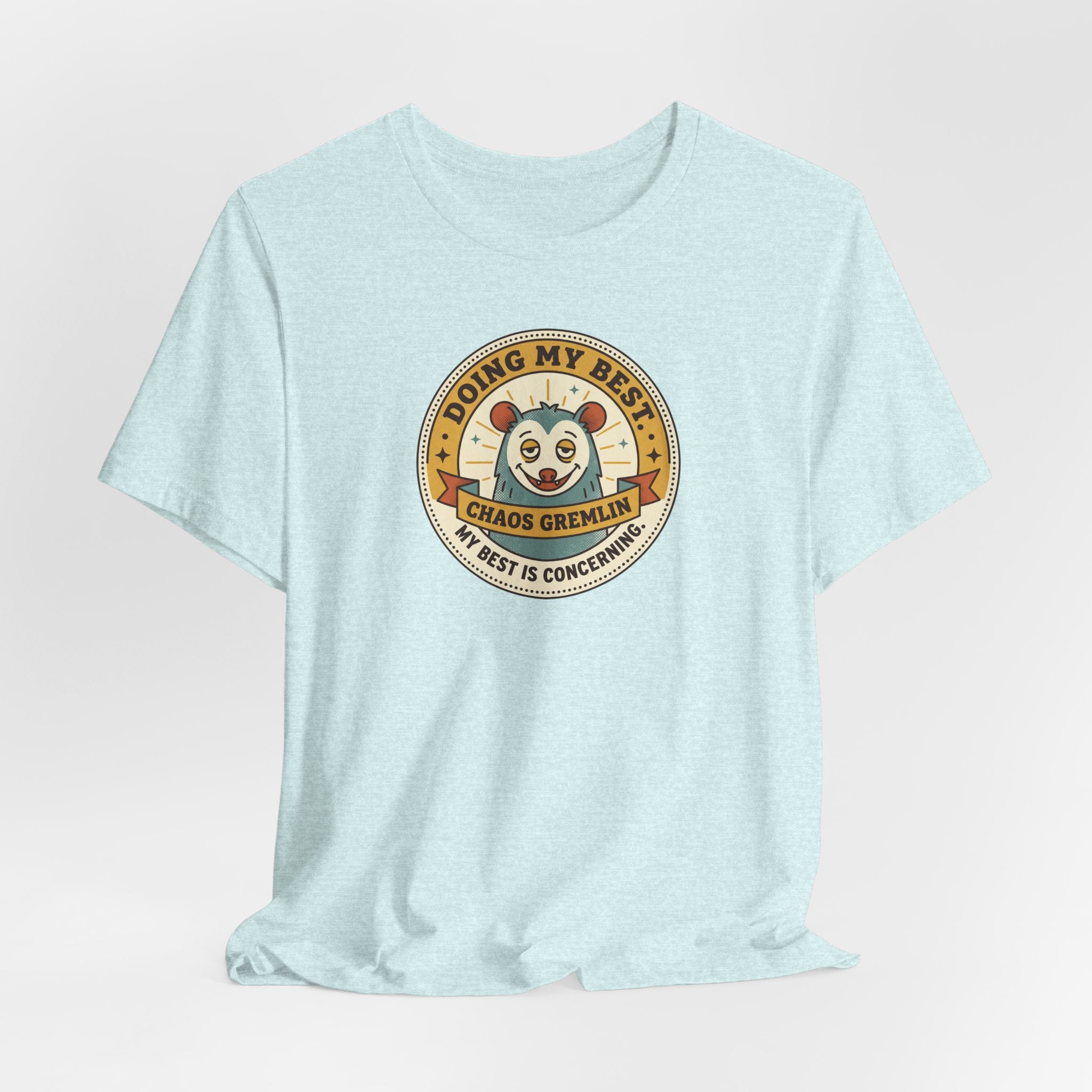 Light blue crewneck T-shirt with round cartoon gremlin badge graphic centered on chest